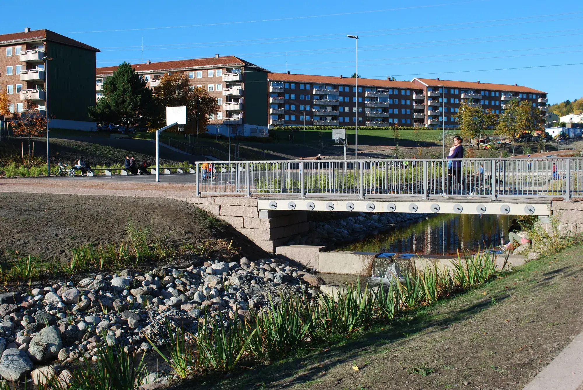 Bjerkedalen park, à Økernbråten : le ruisseau rouvert, ses berges empierrées et une passerelle, immeubles des années 1950, octobre 2013