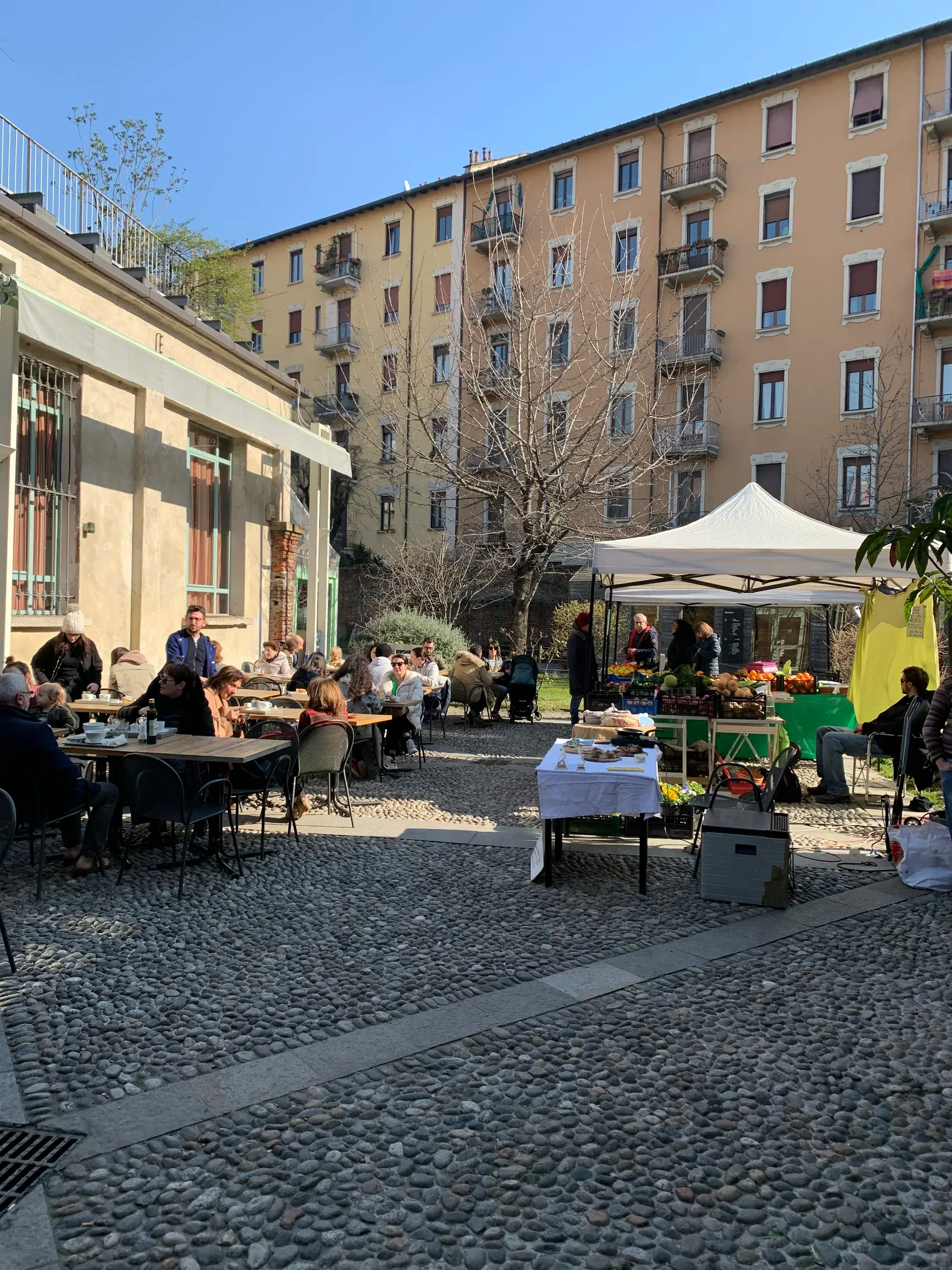 Cour pavée de galets au soleil : terrasse pleine