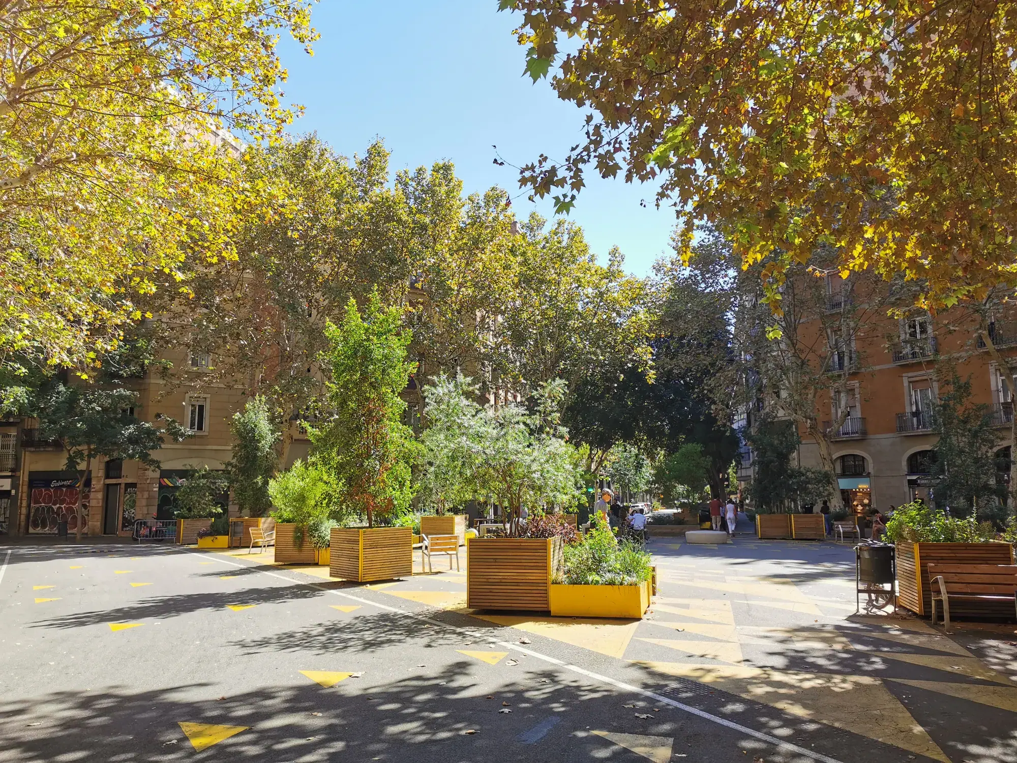 Sant Antoni : bacs en bois, bancs et marquage jaune sur l’ancienne chaussée.